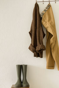 Close-up of clothes hanging over rubber boots against wall