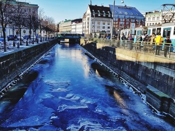 Bridge over canal in city against sky