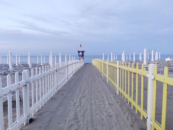 Footpath on beach over sea against sky