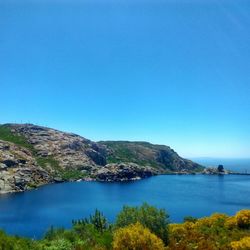 Scenic view of sea and mountains against clear blue sky