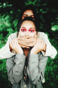 Portrait of beautiful young woman standing against plants