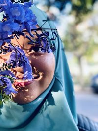 Close-up portrait of woman wearing hijab by flowers