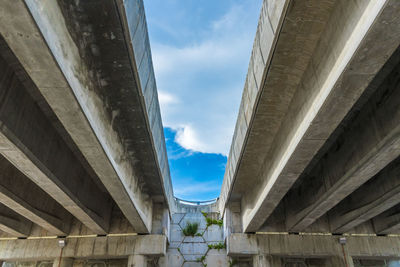 Low angle view of bridge amidst buildings against sky