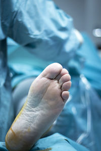 Low section of patient lying on bed in hospital