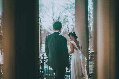 Rear view of couple standing against window