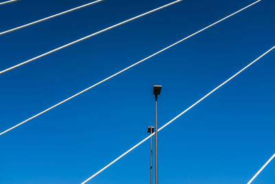 Low angle view of power lines against blue sky