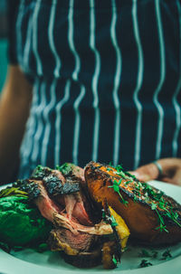 Midsection of person holding meat plate