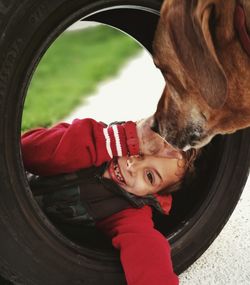 Portrait of happy boy playing with tire by dog on footpath