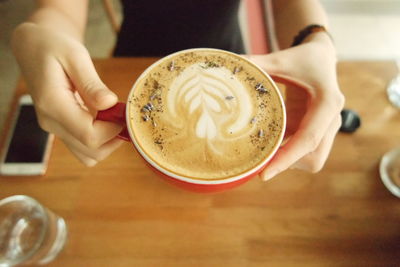 Woman holding coffee cup over table