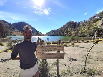 Portrait of young man standing on mountain against sky