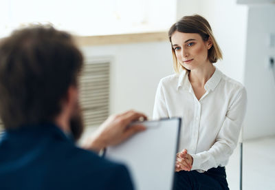 Side view of young businesswoman using laptop while sitting at office