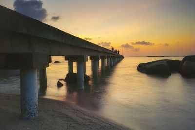 Pier over sea against sky during sunset