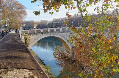 Arch bridge over river against sky during autumn