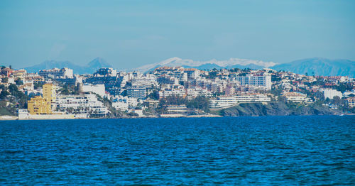 Scenic view of sea by buildings in city against sky