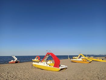 Boat moored on beach against clear sky