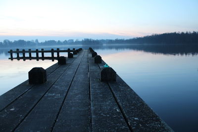 Pier over lake against sky during sunset