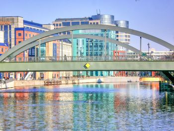 Bridge over river by buildings against sky