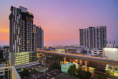 Modern buildings in city against sky during sunset