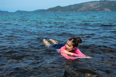 Young woman looking away while relaxing in sea