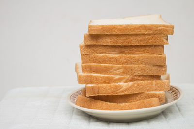 Close-up of bread in plate against white background