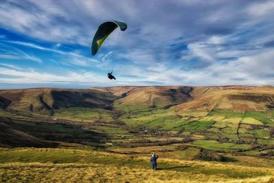 Man paragliding over mountain against sky