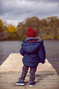 Child boy in knitted red hat and scarf in autumn on the street