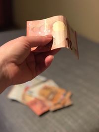 Close-up of hand holding paper currency indoors