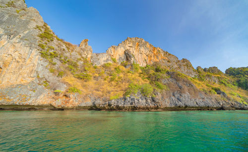 Scenic view of sea and rocks against blue sky