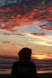 Rear view of silhouette man standing against orange sky