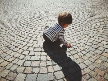 High angle view of toddler girl sitting on cobbled street