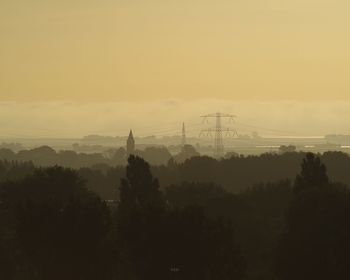 Silhouette of electricity pylon against sky