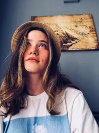 Low angle view of thoughtful woman wearing hat against wall