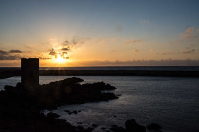 Tower by sea against sky during sunset at castelsardo