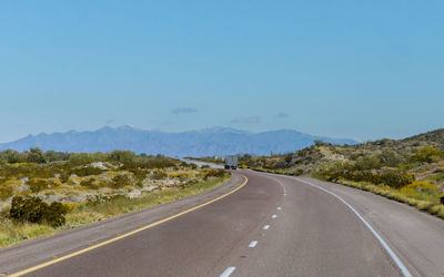 Road leading to mountains against blue sky