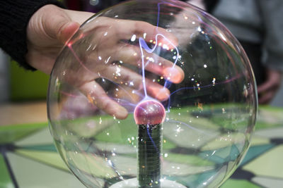 Close-up of hand holding glass against water