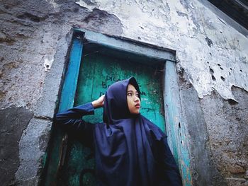 Portrait of woman standing against wall