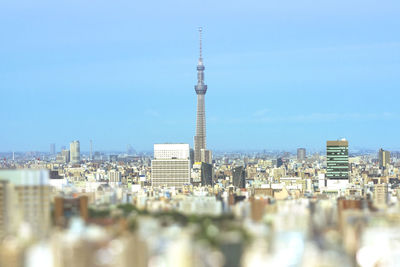 Tilt-shift view of buildings of tokyo with skytree tower against blue sky.