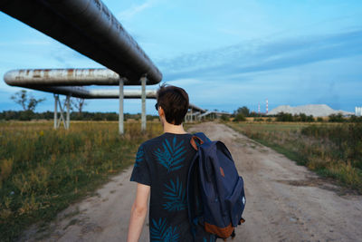 Rear view of man standing on field against sky