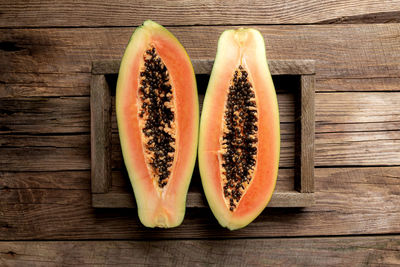 Fresh tropical papaya fruit in wooden delivery box on wooden background top view with copy space