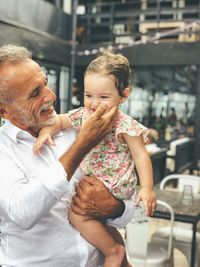 Smiling senior man carrying granddaughter