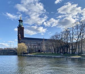 View of buildings by river against sky