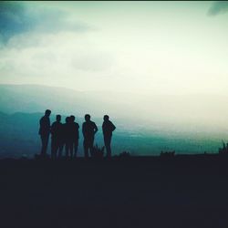 Silhouette of people on landscape against sky