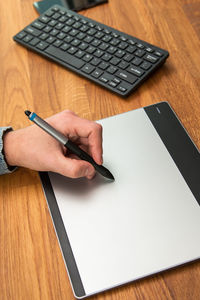 Cropped hand writing in book on table