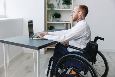 Low section of man using mobile phone while sitting on table