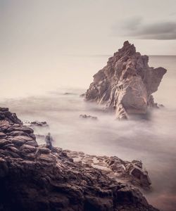 Rock formations on shore against sky