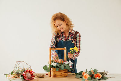 Woman standing by flowering plant against white background