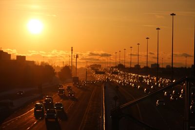 Cars on road in city against sky during sunset