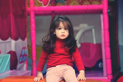 Portrait of cute girl sitting on table at home