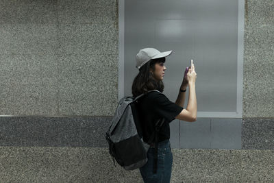Side view of young woman looking away against wall