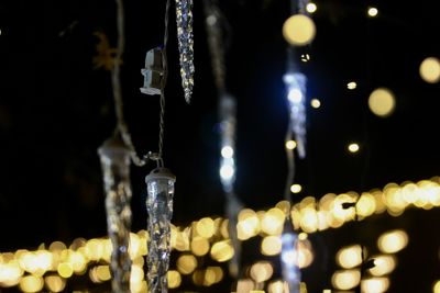 Close-up of illuminated light bulbs hanging at night